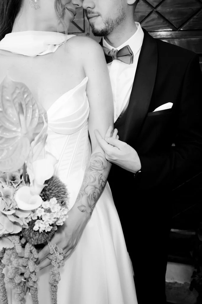 Black and white close-up of a bride and groom touching noses, the bride holding an anthurium and calla lily bouquet, in Trogir, Croatia